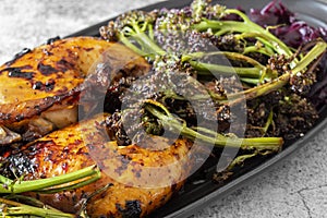 Piri or Peri chicken dinner with roasted broccoli and pickled red cabbage on a black plate.