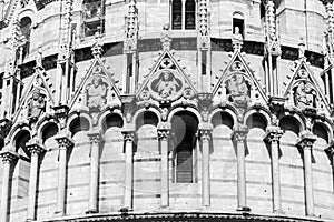 Black and white photo showing in close-up decorative statues on the exterior facade of Basilica in Pisa