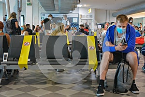 Pisa Airport, PSA, Italy: Young man travelling during coronavirus pandemic. Holidays with COVID-19 mask and social distancing