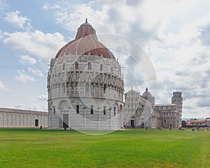 Pisa Baptistry and Cathedral over the lawn of Cathedral Square in Pisa, Italy