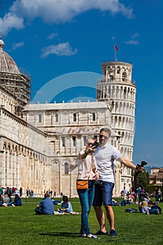 Young couple of tourists taking a selfie in front of the famous Leaning Tower of Pisa