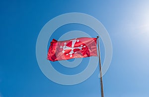 Pisan Cross, the official flag of Pisa province in Italy against blue sky.