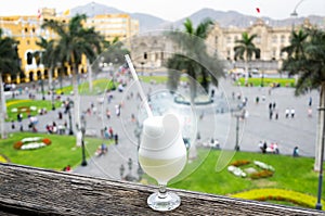Pisco sour homemade cocktail with the background of the main square of Lima photo