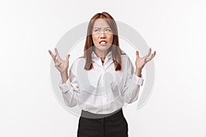 Pissed-off asian woman hates annoying clients. Distressed and tensed irritated female in white shirt, squeez hands in