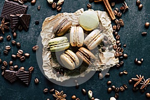 Pistachio chocolate coffee and vanilla flavored macaroons with pieces of chocolate cinnamon sticks coffee beans and pistachios