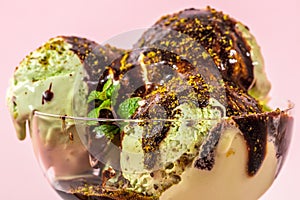 pistachio ice cream decorated chocolate topping and nuts on pink background