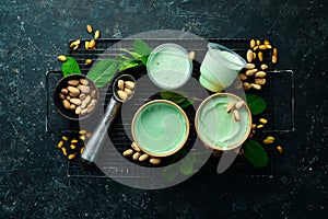 Pistachio ice cream with mint and pistachios. Ice cream spoon. On a black stone background