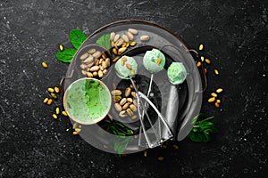 Pistachio ice cream with mint and pistachios. Ice cream spoon. On a black stone background