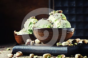 Pistachio ice cream with nuts, decorated with mint leaves, vintage wooden background, selective focus