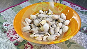 Pistachio nuts falling into bowl, slow motion