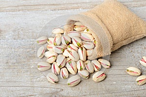 Pistachio nuts with shell in the sack, on the wooden board