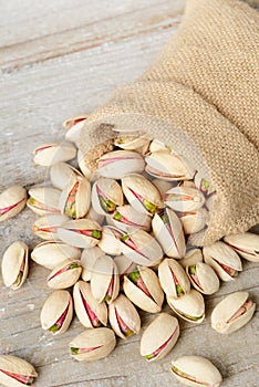 Pistachio nuts with shell in the sack, on the wooden board