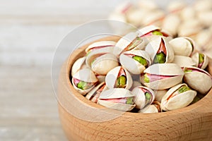 Pistachio nuts with shell in the wooden bowl, on the wooden board
