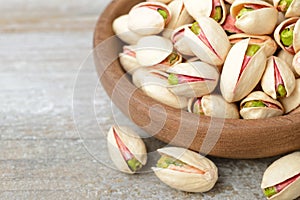 Pistachio nuts with shell in the wooden plate, on the wooden board