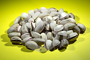 Pistachio nuts on yellow background.