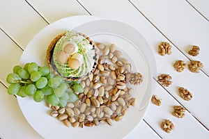 Pistachios, a bunch of grapes, cake and walnuts on white boards. Country breakfast