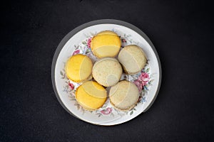 Pistachios and orange macaroons arranged on a black background