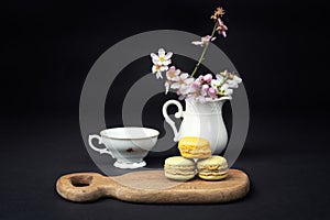 Pistachios and orange macaroons arranged on a black background