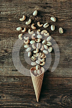 Pistachios in waffle cone on wooden table, healthy snack, concept flat lay photography and content for food blog