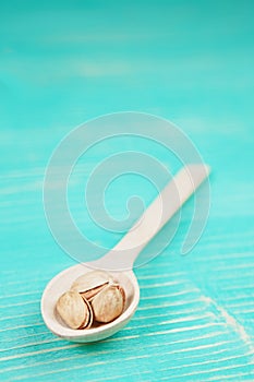 Pistachios on wooden spoon over wooden vintage background.