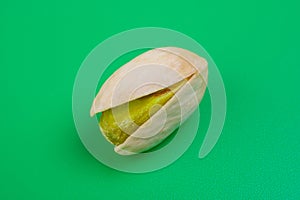 pistacho abierto con el fruto sin piel sobre fondo verde photo
