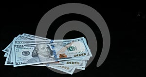 Pistol falling on 100 US Dollars Banknotes against Black background