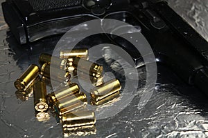 Pistol gun detail with brass golden munition on shiny silver desk photo