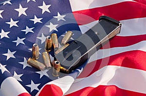 A pistol magazine with bullets on an American flag