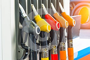 Pistols of gasoline fueling cars at the station, against the backdrop of a truck wheel.