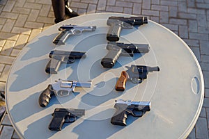 Pistols and revolvers on the table among weapons, selective focus. Crime news background