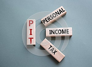 PIT - Personal Income Tax symbol. Wooden cubes with words PIT. Beautiful grey green background. Business and PIT concept. Copy