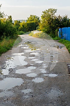 Pit on village road with water after the rain on sunset