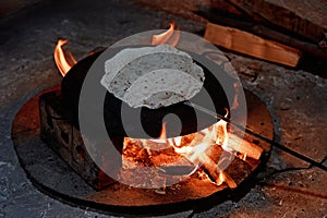 Pita bread baking on a saj or tava on fire, close-up.