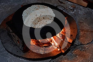 Pita bread baking on a saj or tava on fire, close-up