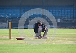 Pitch curator removing extra grass from wicket.