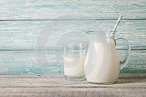 Pitcher and glass of milk on wooden table