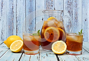 Pitcher of iced tea with two glasses on rustic blue wood