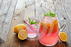 Pitcher of pink lemonade with filled glass on rustic wood