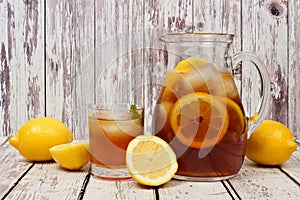 Pitcher of summer iced tea with glass on rustic white wood