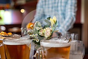 Pitchers of beer and fresh flowers on a restaurant table