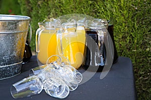 Pitchers with cola and orange with ice and glasses to serve at an outdoor event. Catering and hospitality service concept