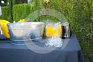 Pitchers with cola and orange with ice and glasses to serve at an outdoor event. Catering and hospitality service concept