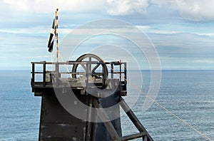 The pithead of a Cornish tin mine showing the main lifting pulley, with a Cornish nationalist Kernow flag