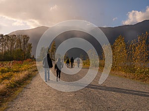 Pitt lake& x27;s beautiful trail with tourists and a mountainous landscape on the background in autumn