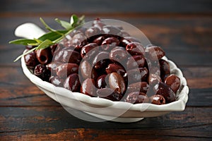 Pitted kalamata olives in bowl on rustic wooden background