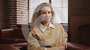 Pivoting around a young caucasian woman portrait looking at camera indoors