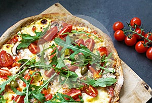 Pizza with arugula, tomato, olive, hollandaise sauce and mozzarella