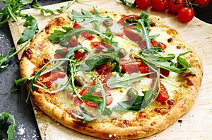 Pizza with arugula, tomato, olive, hollandaise sauce and mozzarella