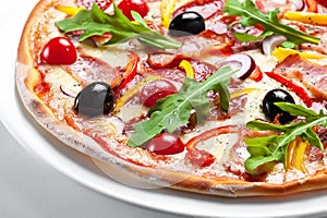 Pizza with bacon, olives and red pepper on a white plate