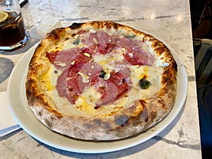 Pizza with bacon, pepperoni, melted cheese, olives served at Local Restaurant